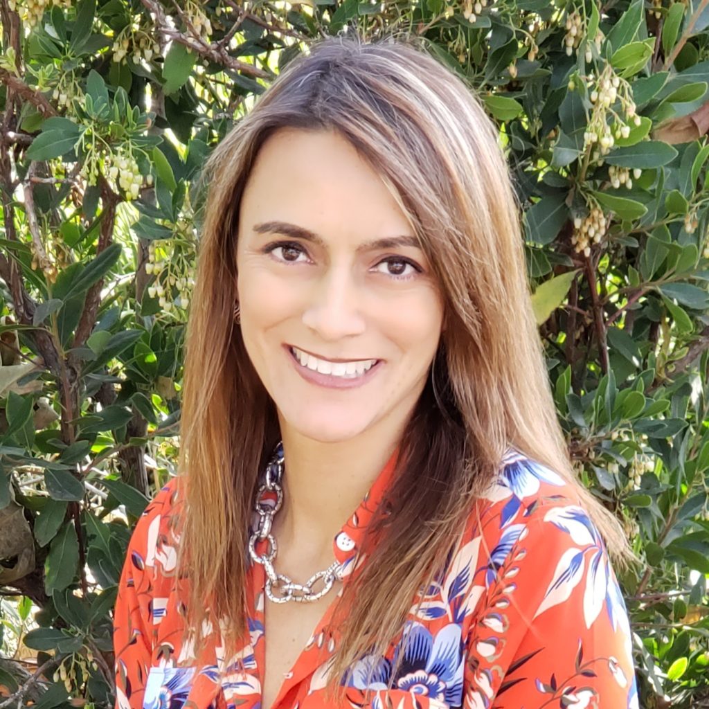 Cristina wearing a floral shirt with a Greenery background